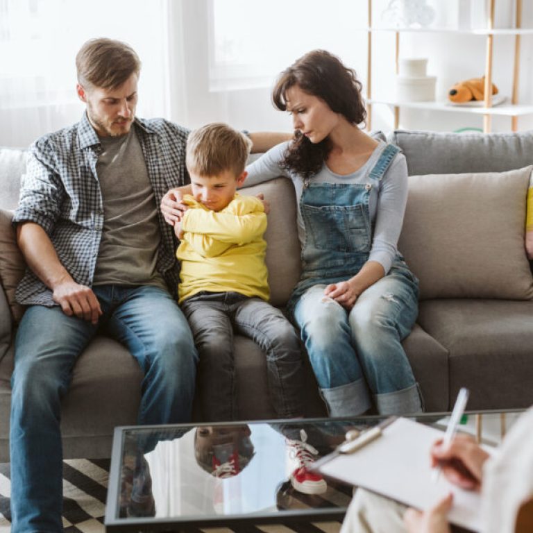 Caring parents and misbehaving boy during therapy session with counselor
