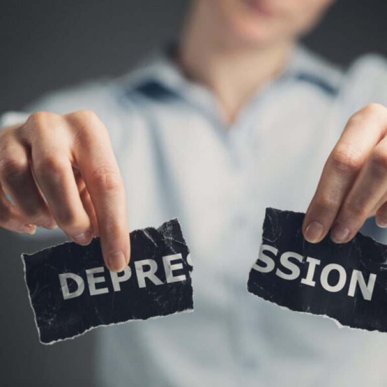 Woman holding a torn label with the word depression toward the camera.