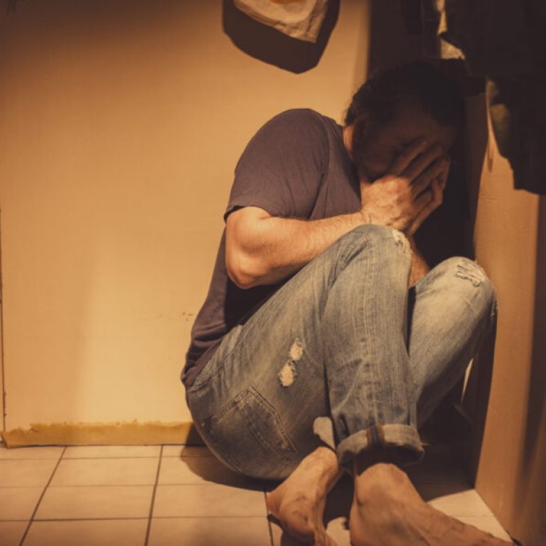 Man sitting in a corner, sad, depressed and lonely, crying