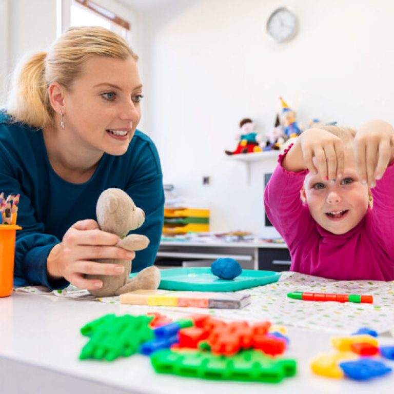 Toddler girl in child occupational therapy session doing sensory playful exercises with her therapist.